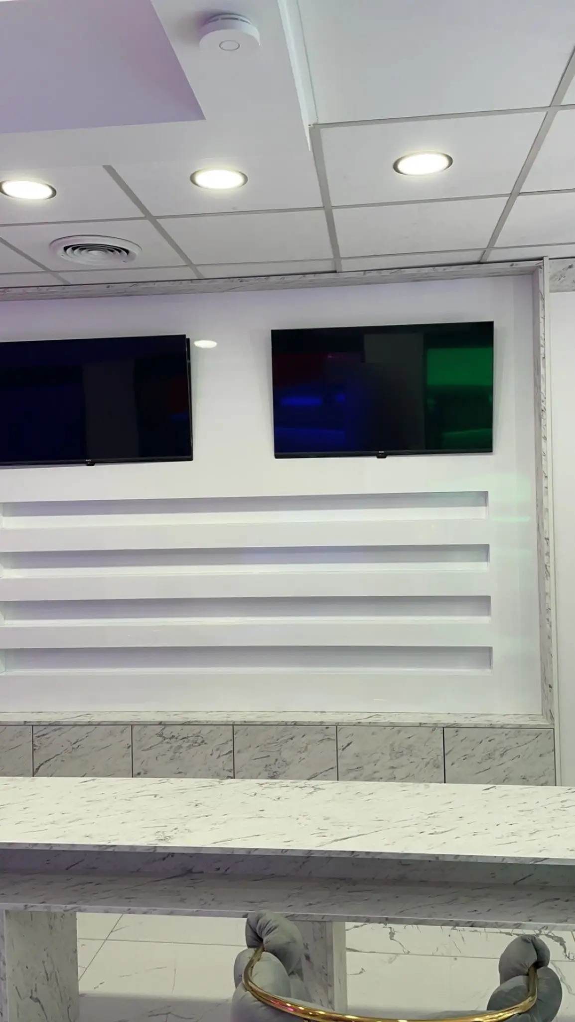Mur de présentation avec quatre étagères laquées blanches retro-eclairees et deux ecrans